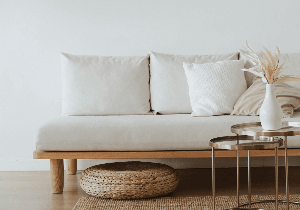 A white sofa with gold table and woven rug.