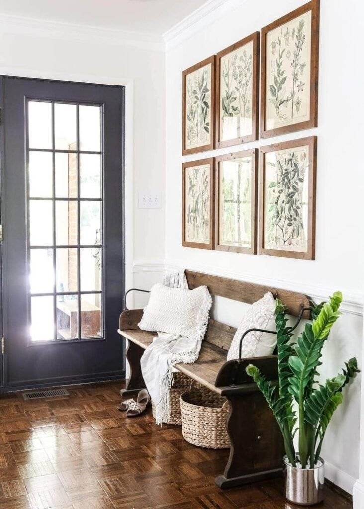 A rustic wooden bench with a gallery wall and a plant.