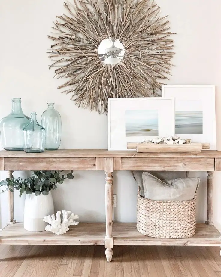 A wooden console table with a wooden mirror, a woven basket and sea frames.