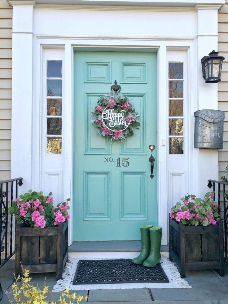 A blue front door with an Easter wreath and pink flowers in wooden planter boxes.