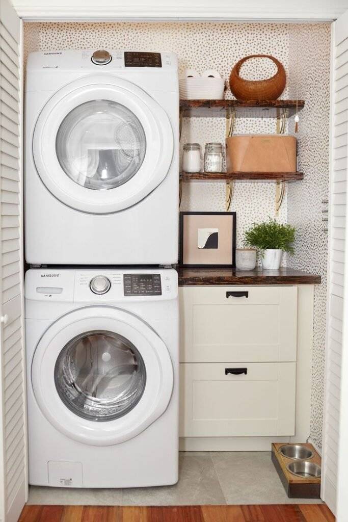 A laundry closet with dotted wallpaper, wooden shelves and golden touches for a luxury look.