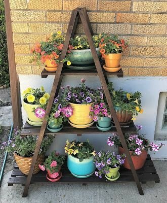 A wooden shelf with colorful plant pots filled with flowers.