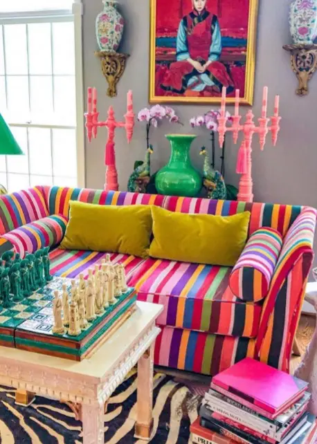 A colorful sofa with a chess game and peacock statues.