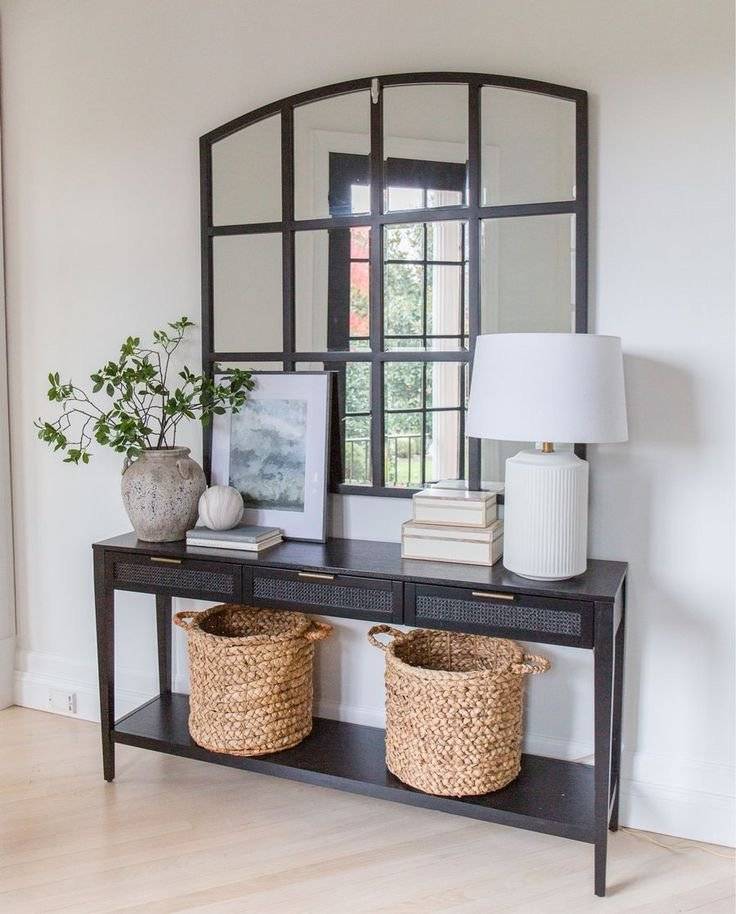 Black window pane mirror with black console table and wooven baskets.