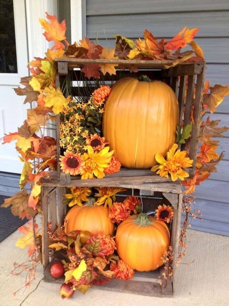 Two wooden crates with pumpkins and tree leaves.