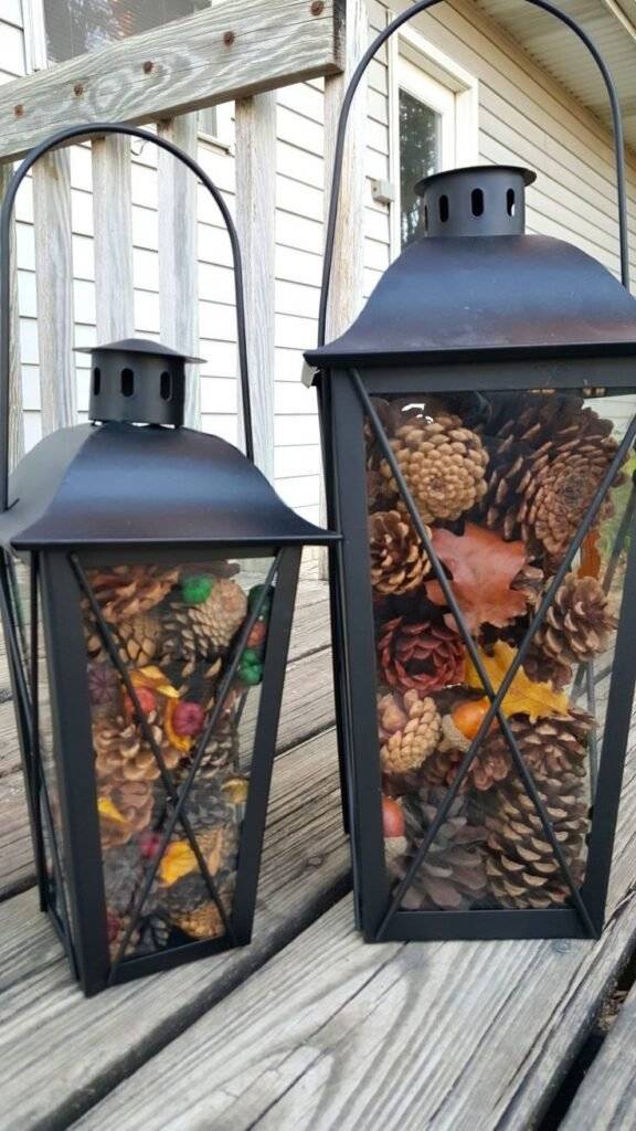 A lantern filled with pine cones and tree leaves.