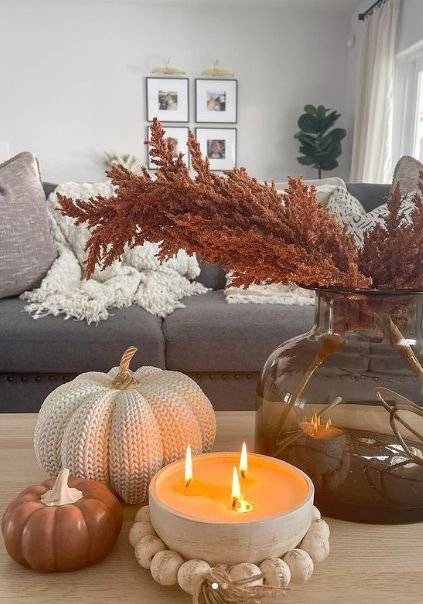 A crochet pumpkin with a candle and a little orange pumpkin.