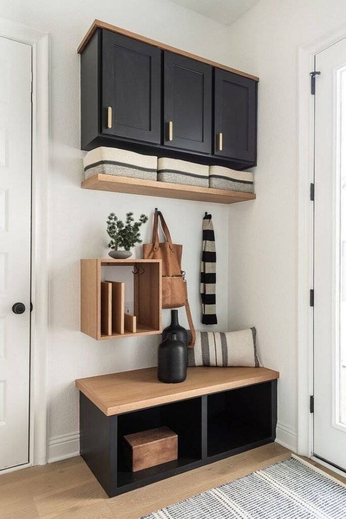 A black entryway cabinet with wooden touches and soft pillows.