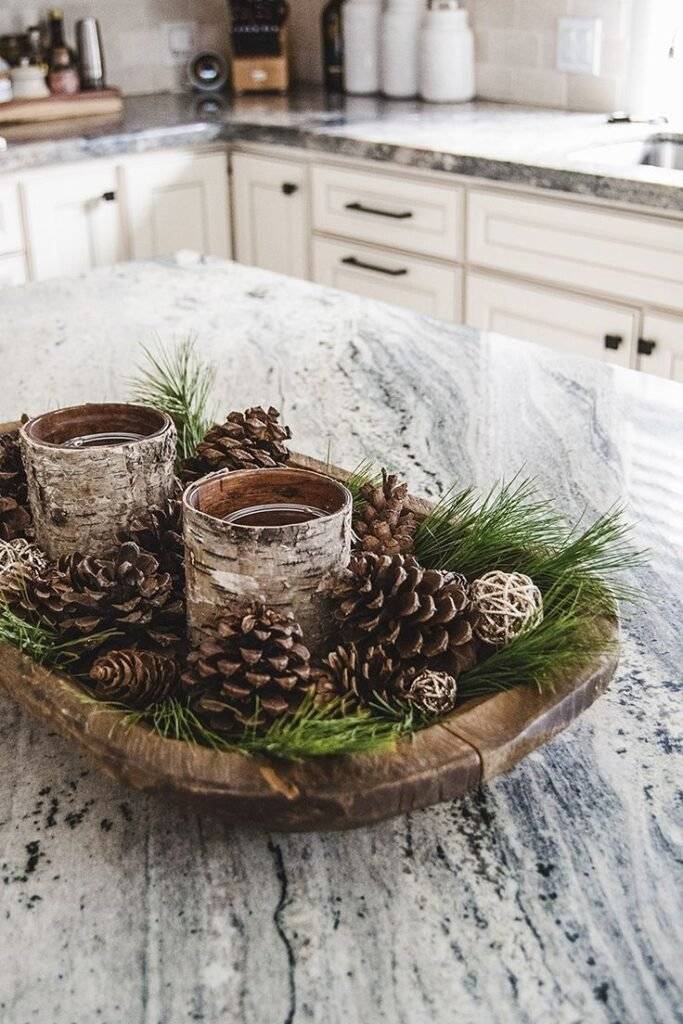 A wooden tray with pine cones, pine branches and candles.