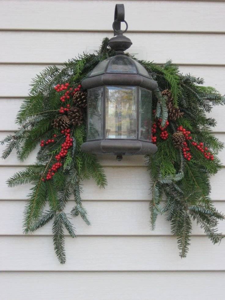 A light fixture with pine branches and red berries.