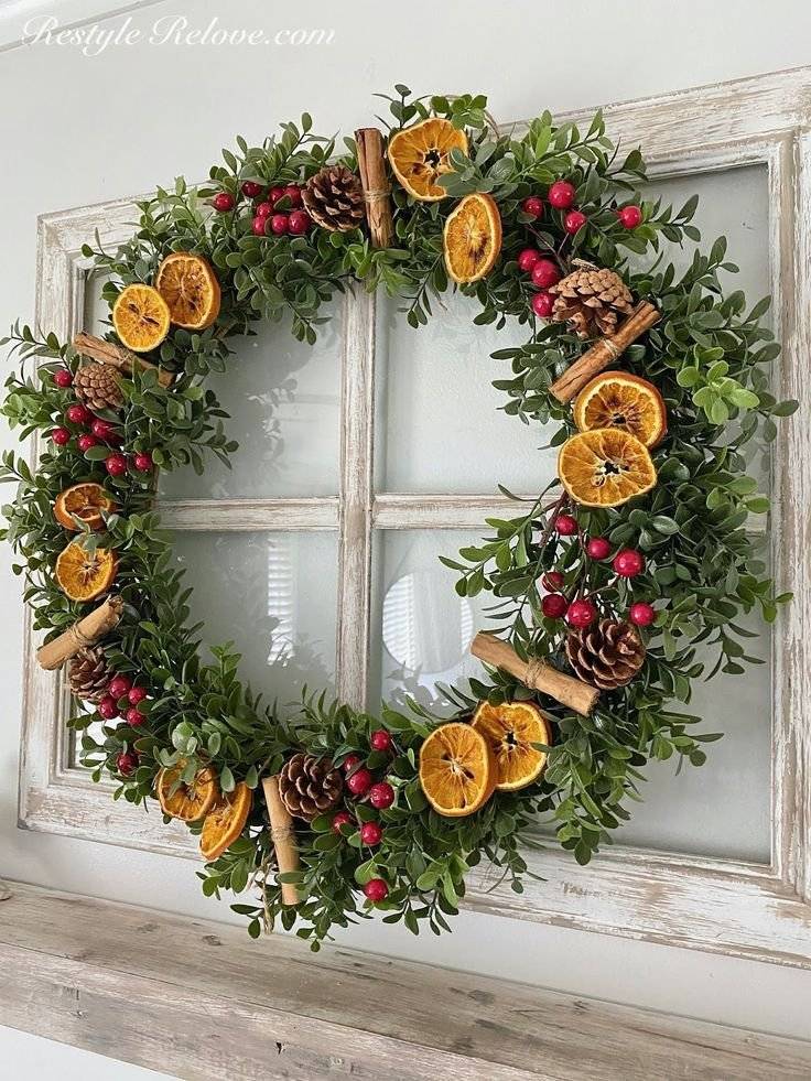 A christmas wreath with pine cones, red berries, orange slices and cinnamon sticks.