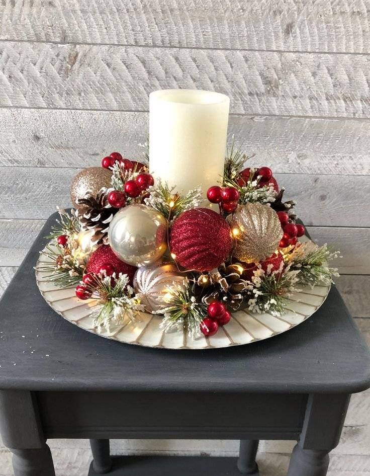 A winter arrangement with Christmas ornaments, pines cones and a candle.