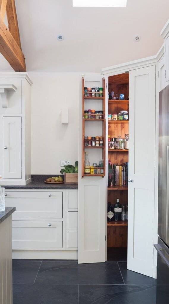 A wooden pantry closet with a spice door rack on the door.