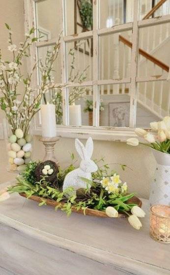 A wooden tray with spring flowers, a rabbit statue and a bird nest.