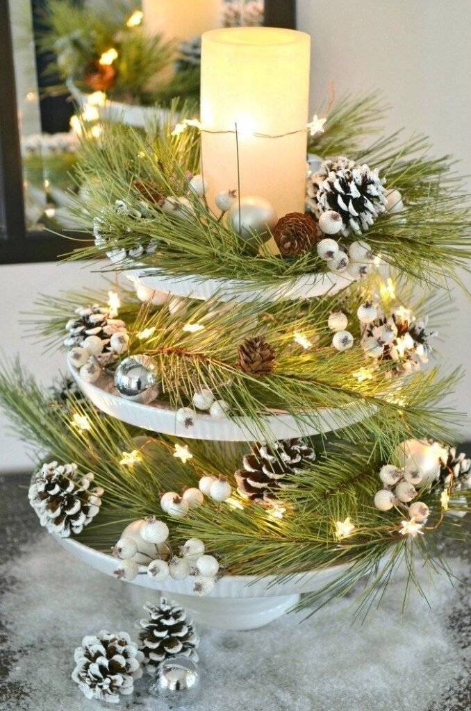 A winter tray with pine cones, pine branches, white berries and a star light garland.