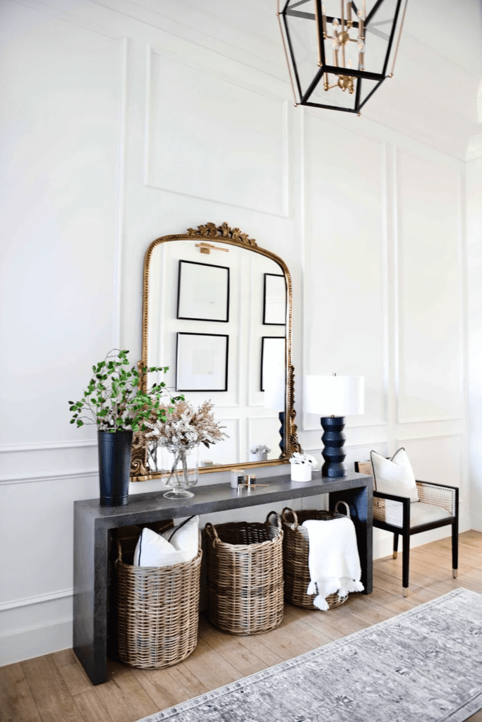 Black concentre console table with golden mirror and woven storage bins.