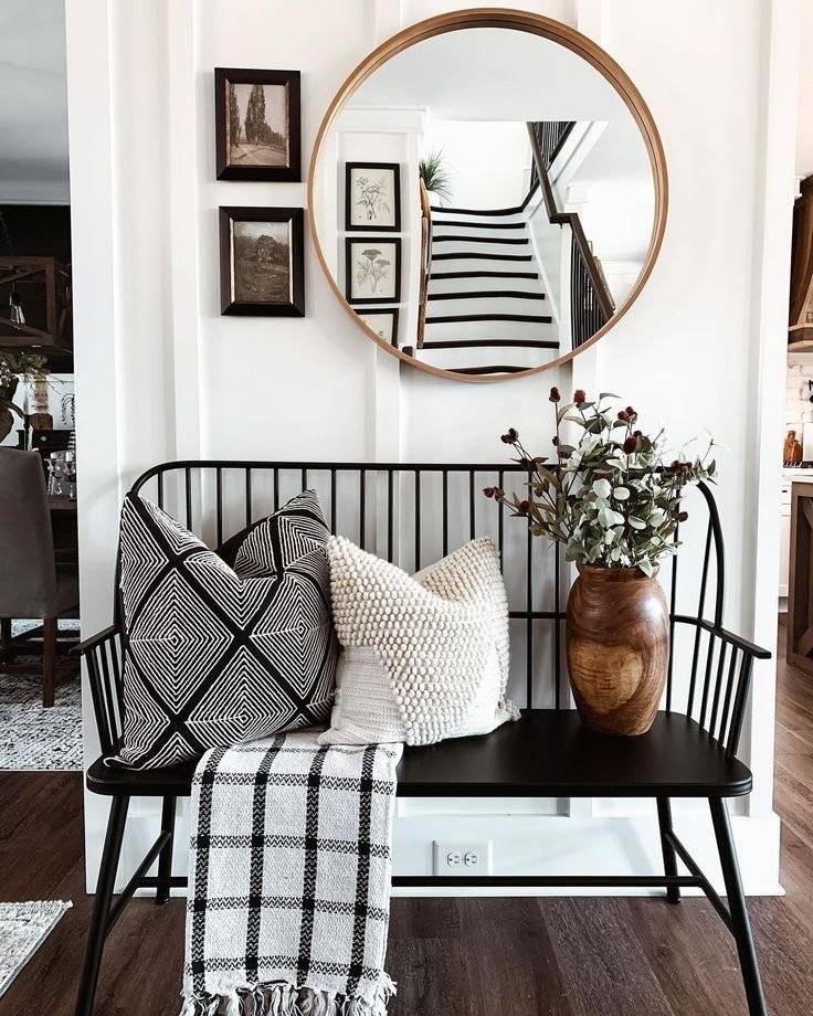 Black metal bench with soft pillows and round mirror.