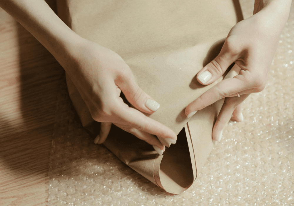 Woman using paper and bubble wrap to protect an item.