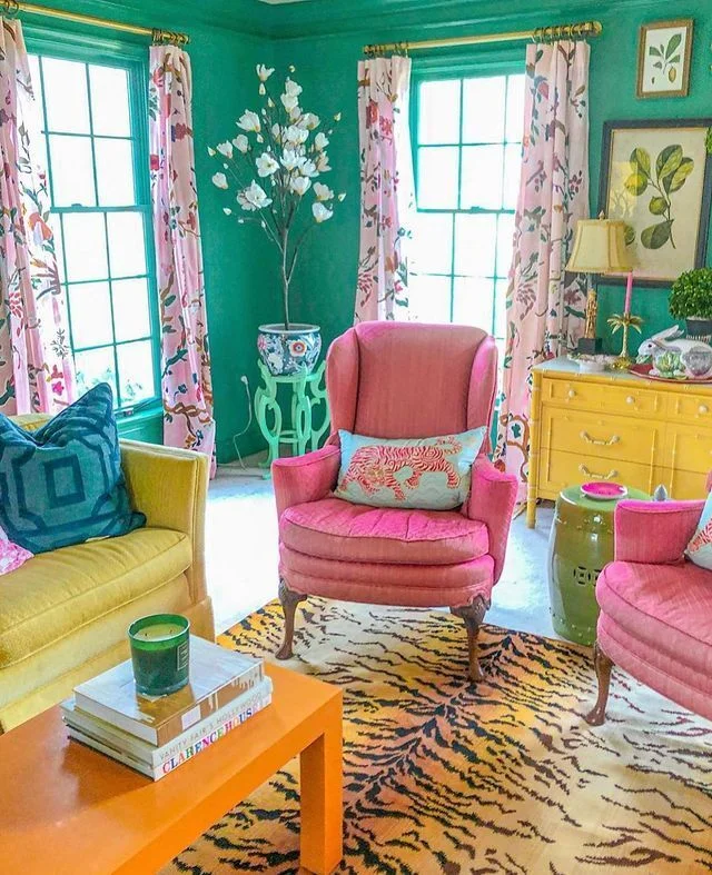 A whimsical living room with antique pink chairs, a yellow sofa and a tiger pattern rug.