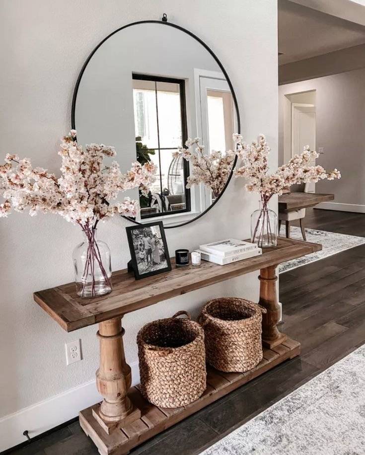 Wooden console table with fake cherry blossom flowers, woven storage bins and round mirror.