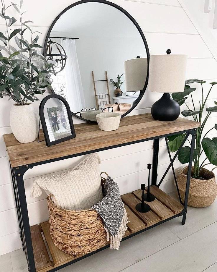 Black round mirror with wooden console table and woven baskets.