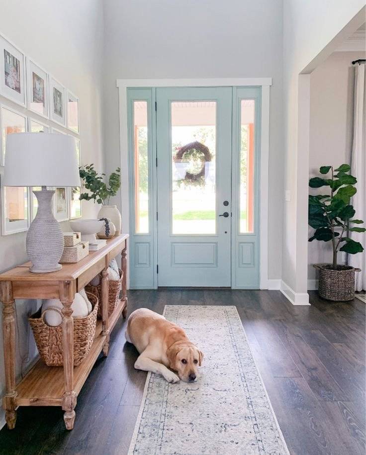 Blue wooden door with wooden console table, woven baskets and a gallery wall.