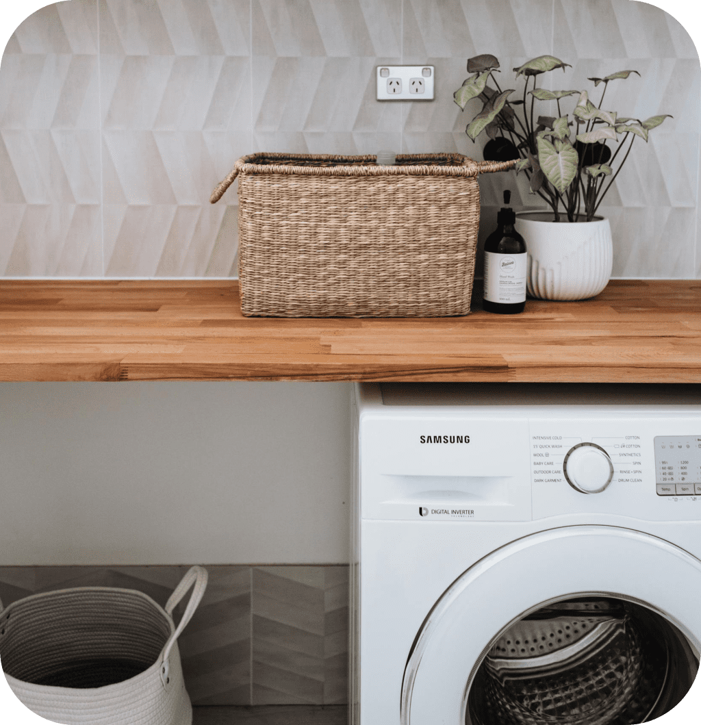 A laundry closet with a washing machine and a wooden countertop.