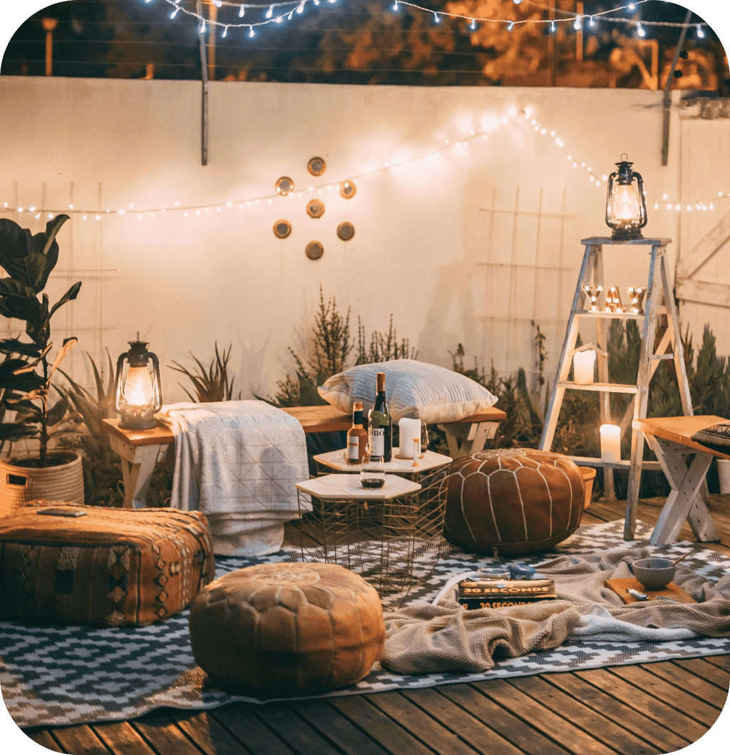 A porch with a rug, benches, comfortable beanbags and blankets.