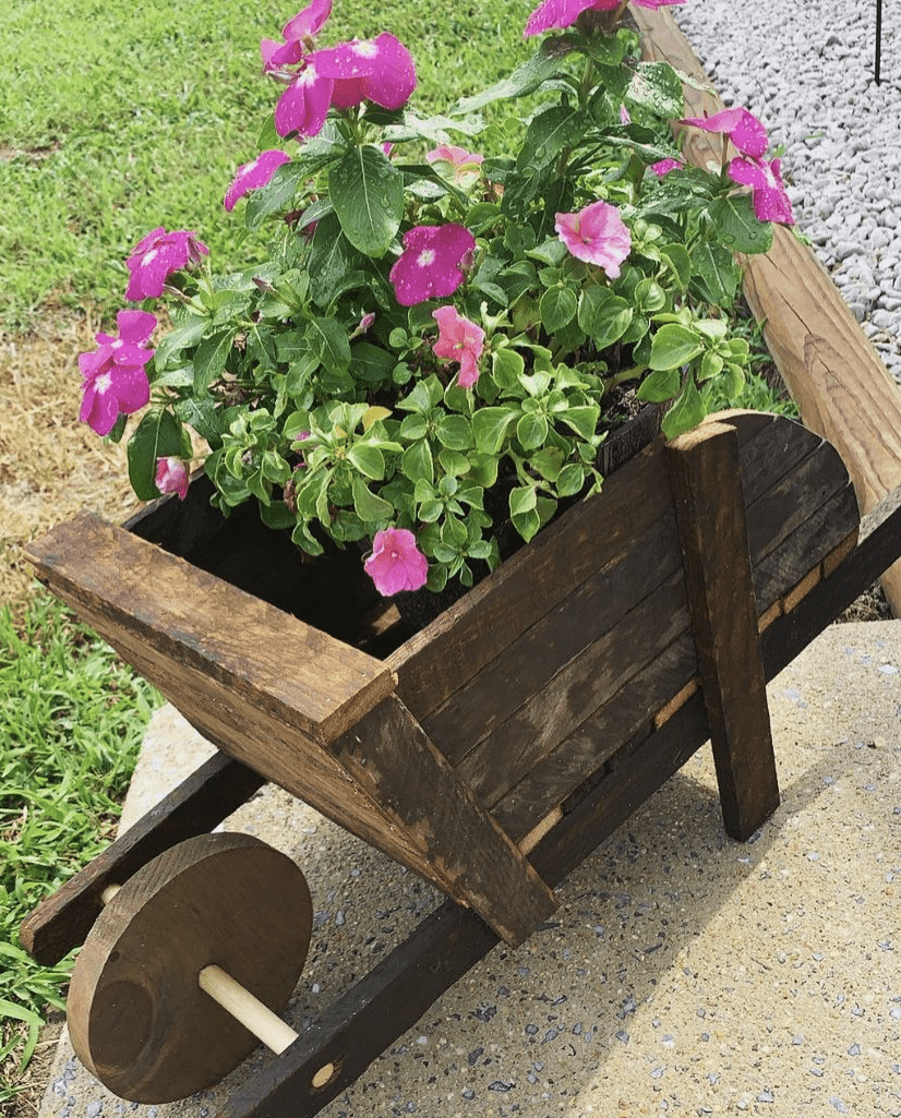 A wooden wheelbarrow used as a flower planter.