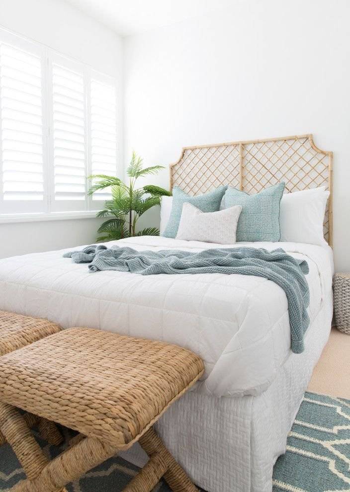 A coastal chic bedroom with a woven headboard and stools.