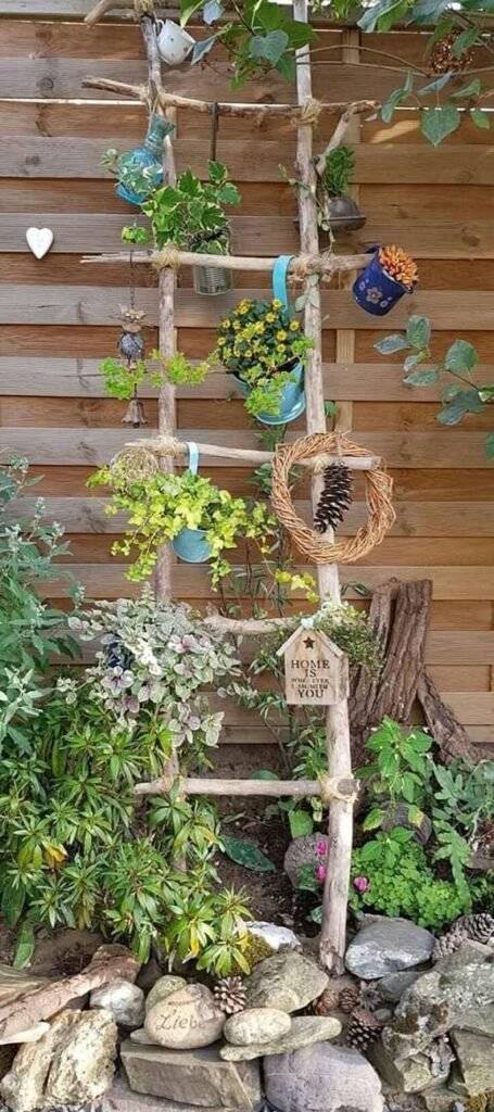 A ladder with flowers, wreath and birdhouse.