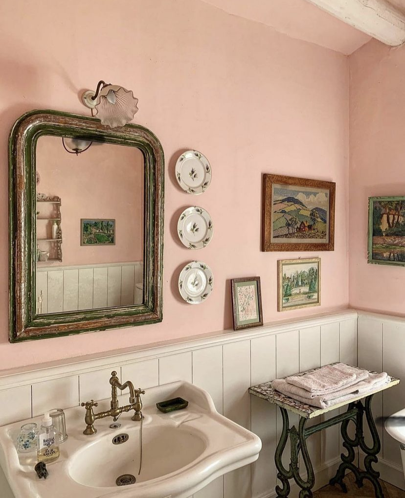 A vintage distressed wooden mirror in a pink bathroom.