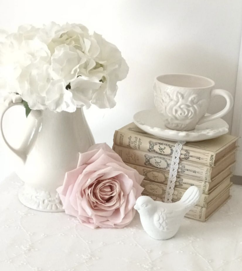 Fake books with lace ribbons, a teacup and flowers.