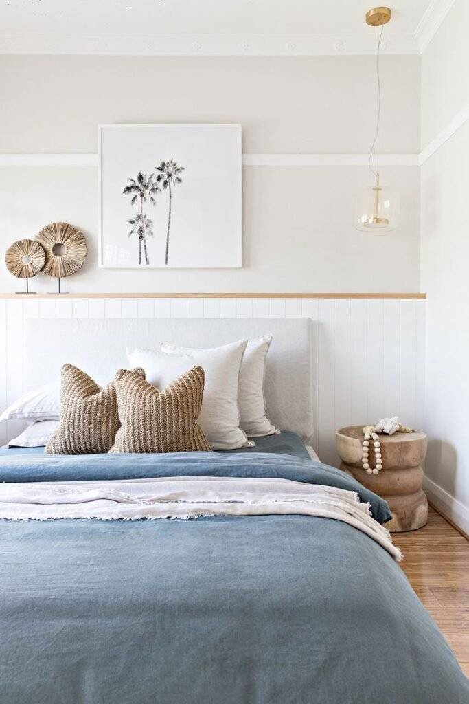 A blue and white bed with a wooden stool and wooden decoration items.