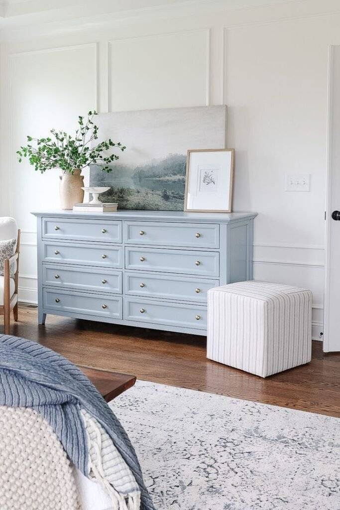 A light blue cabinet with a canva of the sea on top of it.