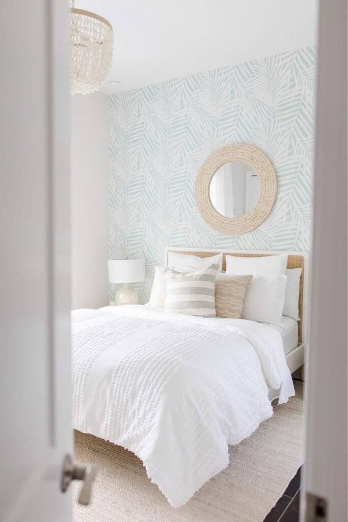 A woven mirror on top of a blue wall with a white feather pattern.