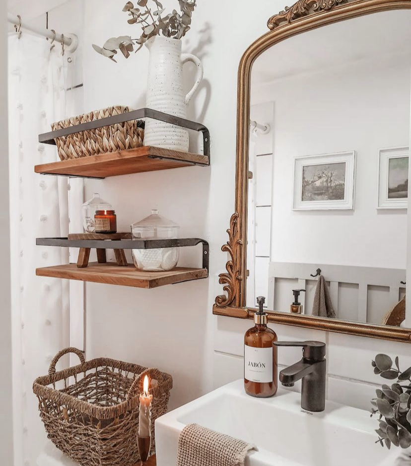 An antique gold bathroom mirror in a neutral bathroom.