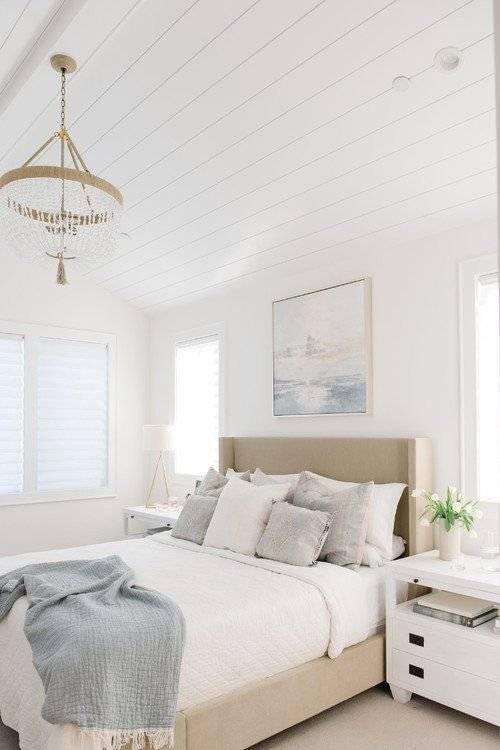 A coastal chic bedroom with a luxury light fixture.