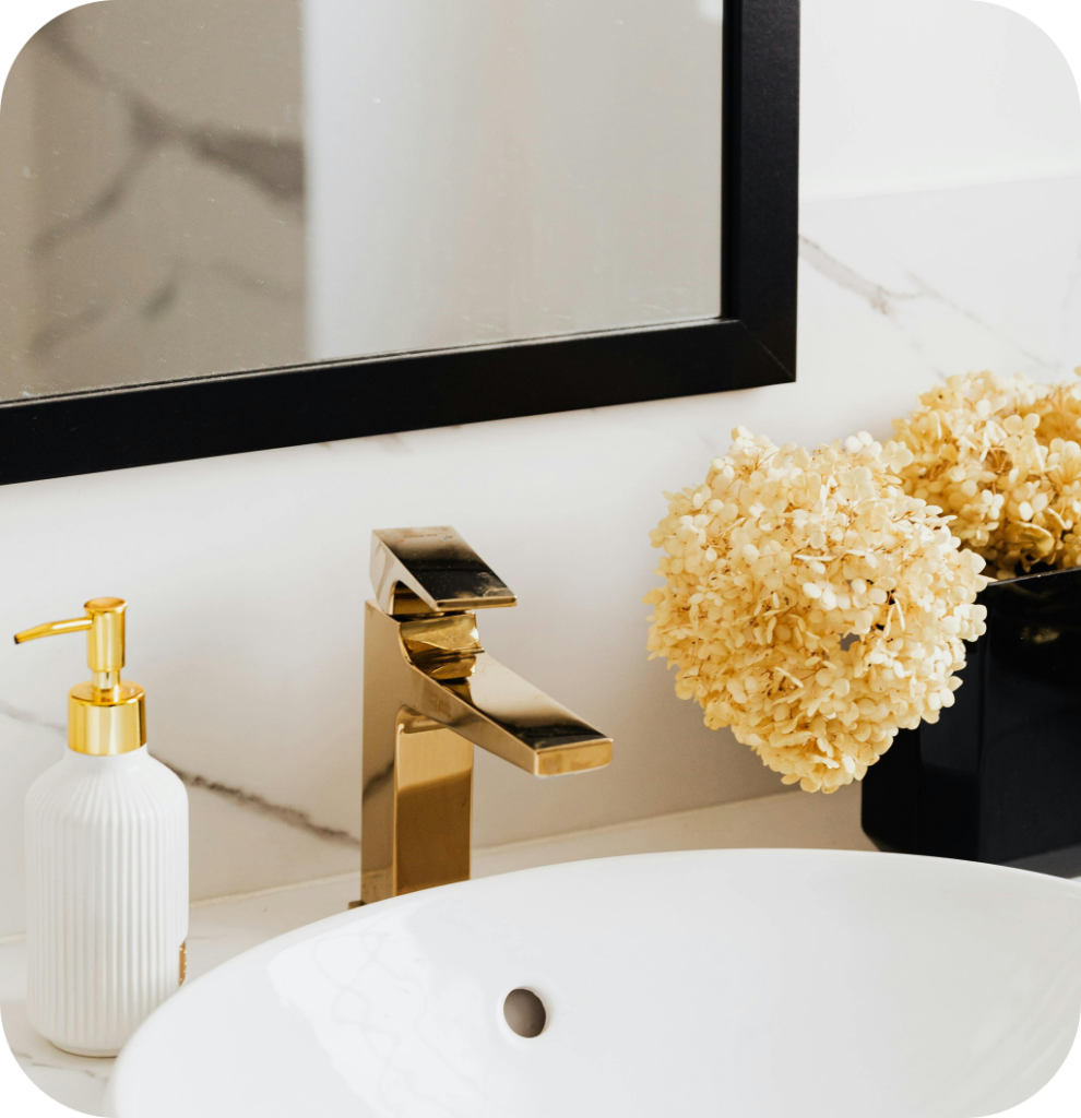 Mirror with black frame above gold faucet.