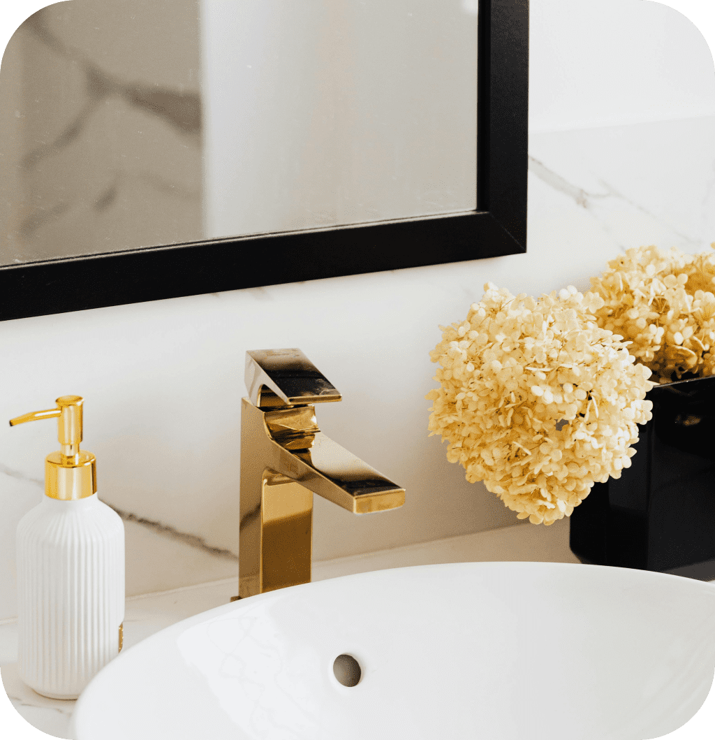 Mirror with black frame above gold faucet.