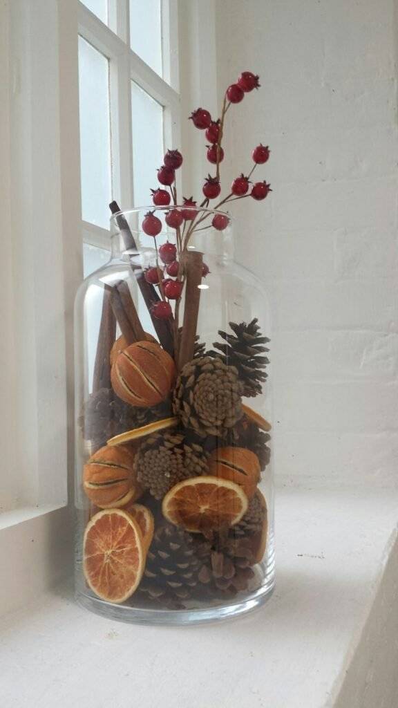 A fall vase with pine cones and cinnamon sticks.