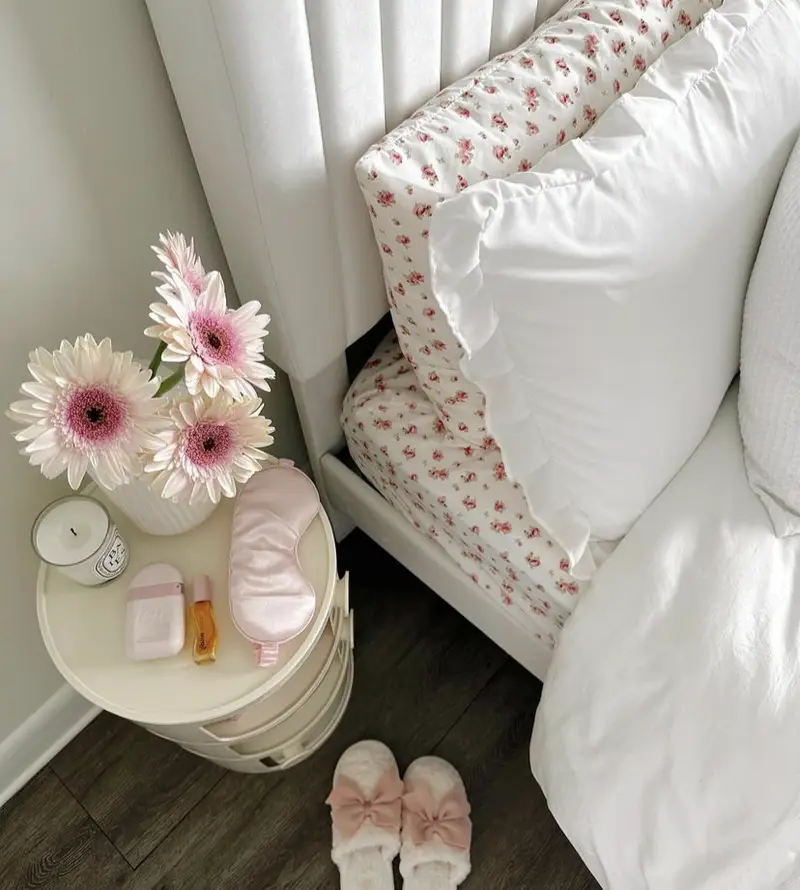 A white bedding set with a floral pattern made of small pink flowers.