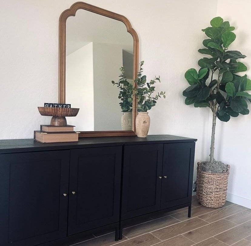A wooden mirror above a black cabinet.