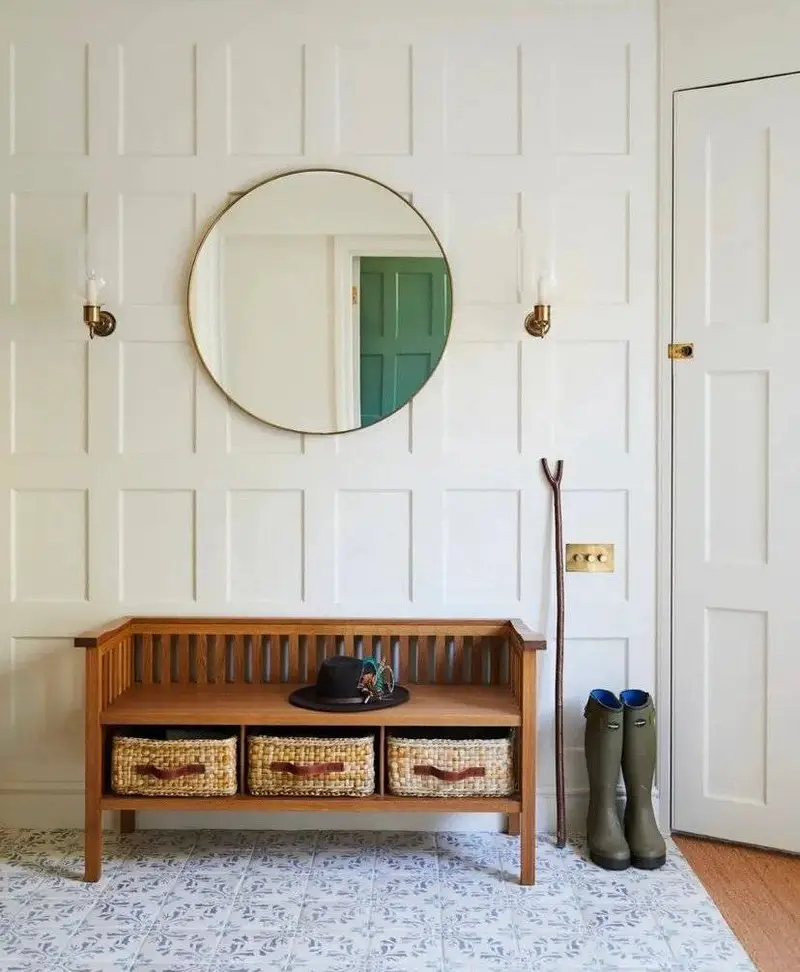 A gold mirror above a wooden bench.