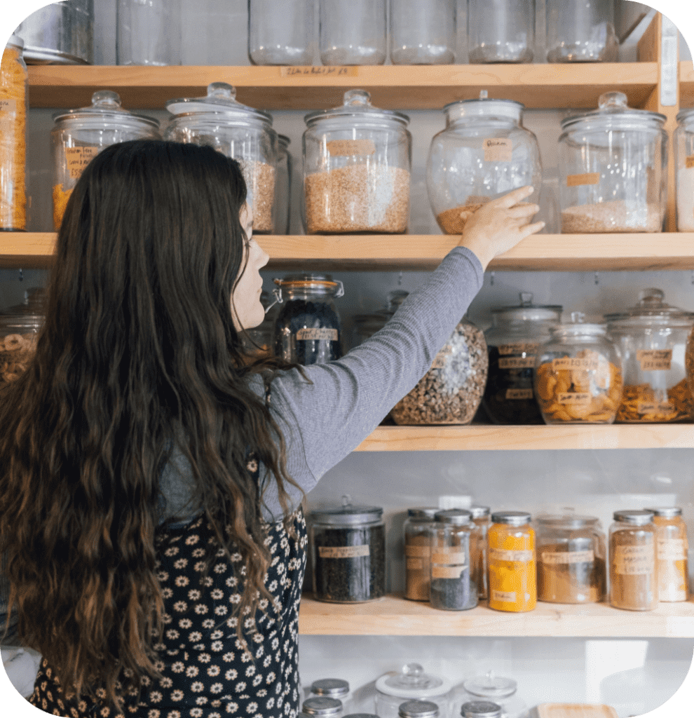 A woman taking a glass jar on a wooden shelf.