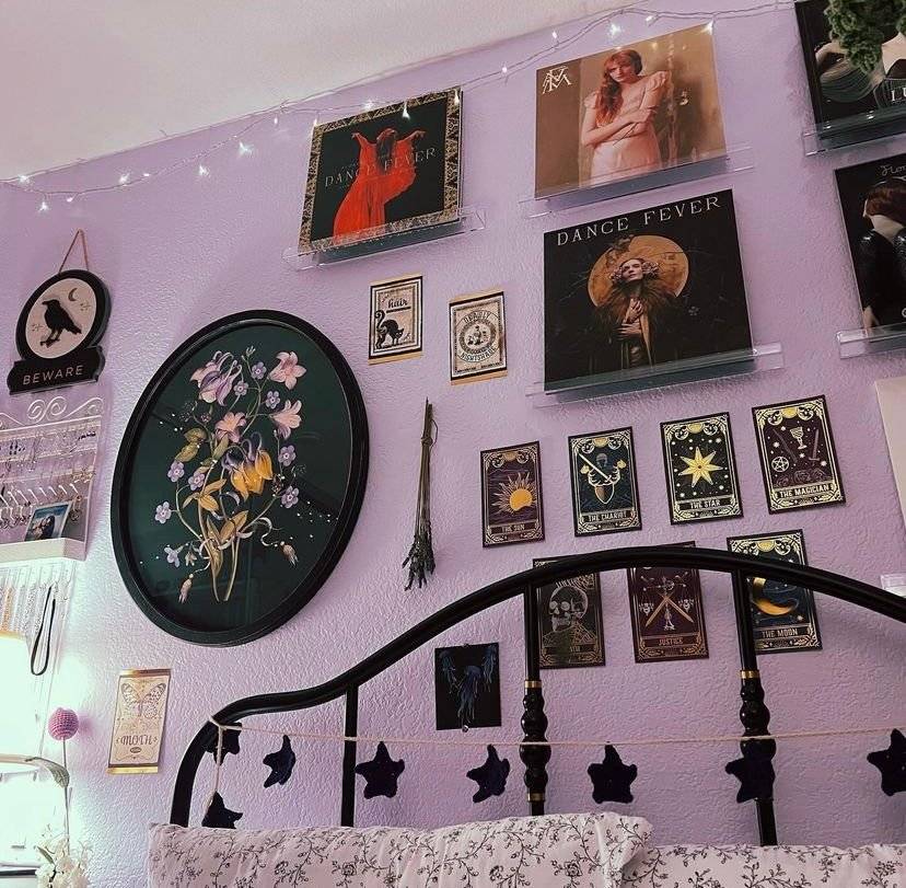 A gallery wall filled with tarot cards, botanical paintings and vinyls.