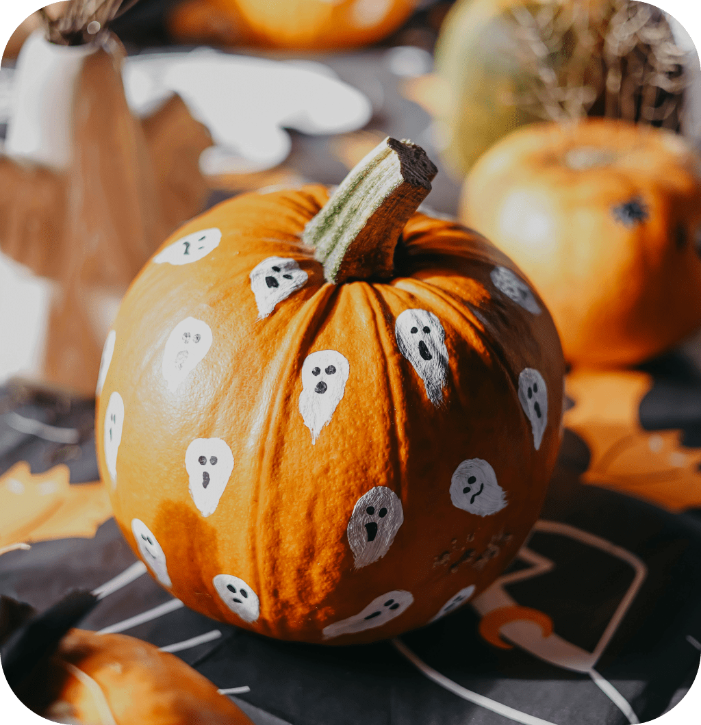 A big orange pumpkin with white ghosts painted on it.