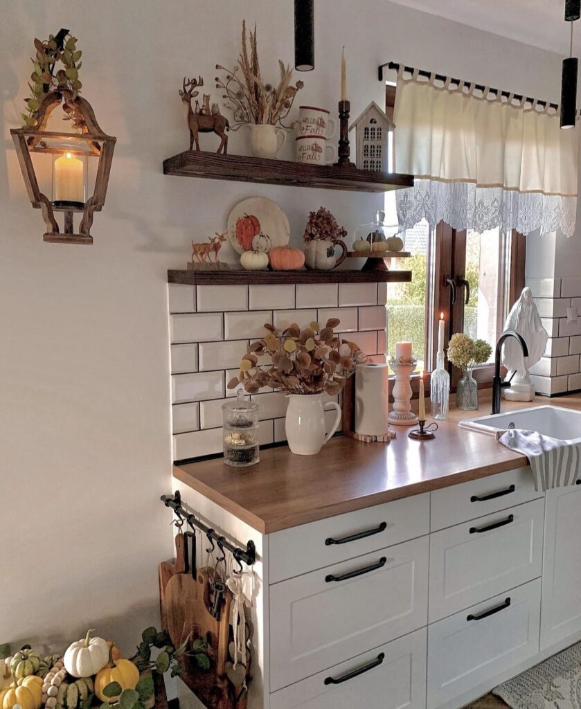 Forest animal figurines with small pumpkins on kitchen shelves.