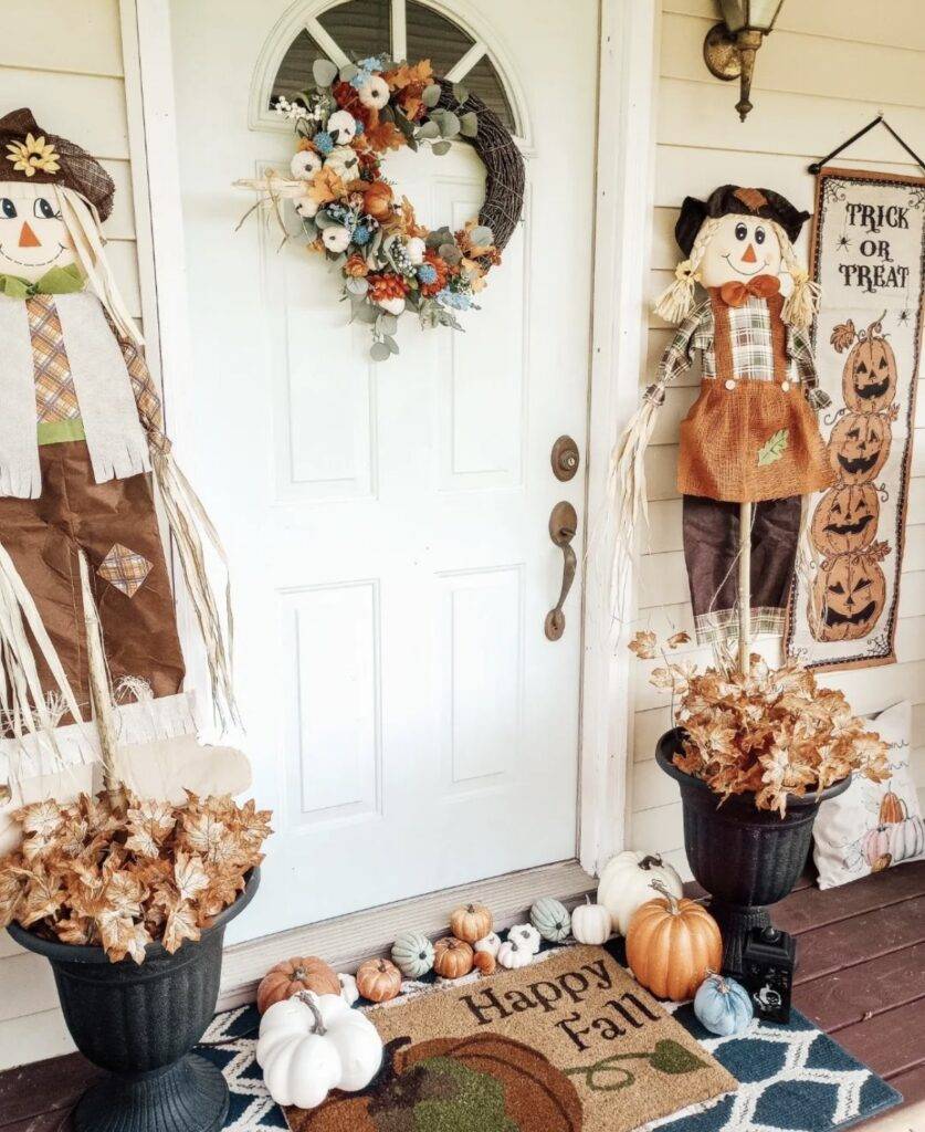 A fall porch with scarecrows and fall leaves.