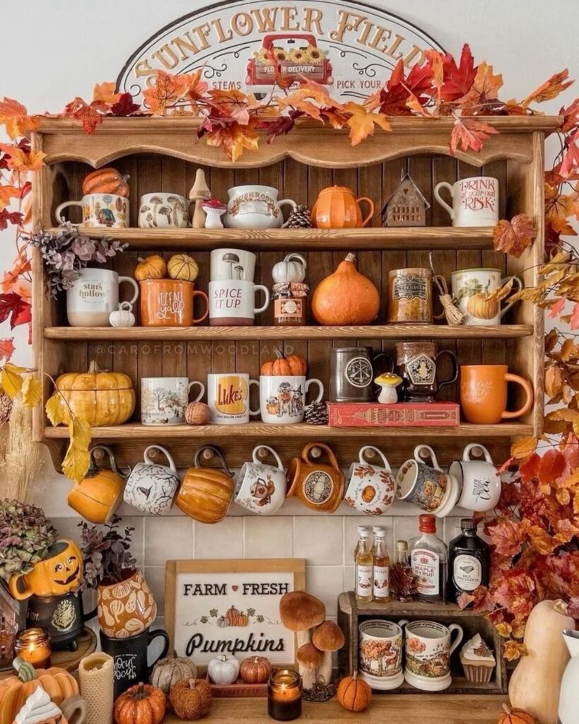 A wooden shelf filled with fall mugs and a maple leaf garland.